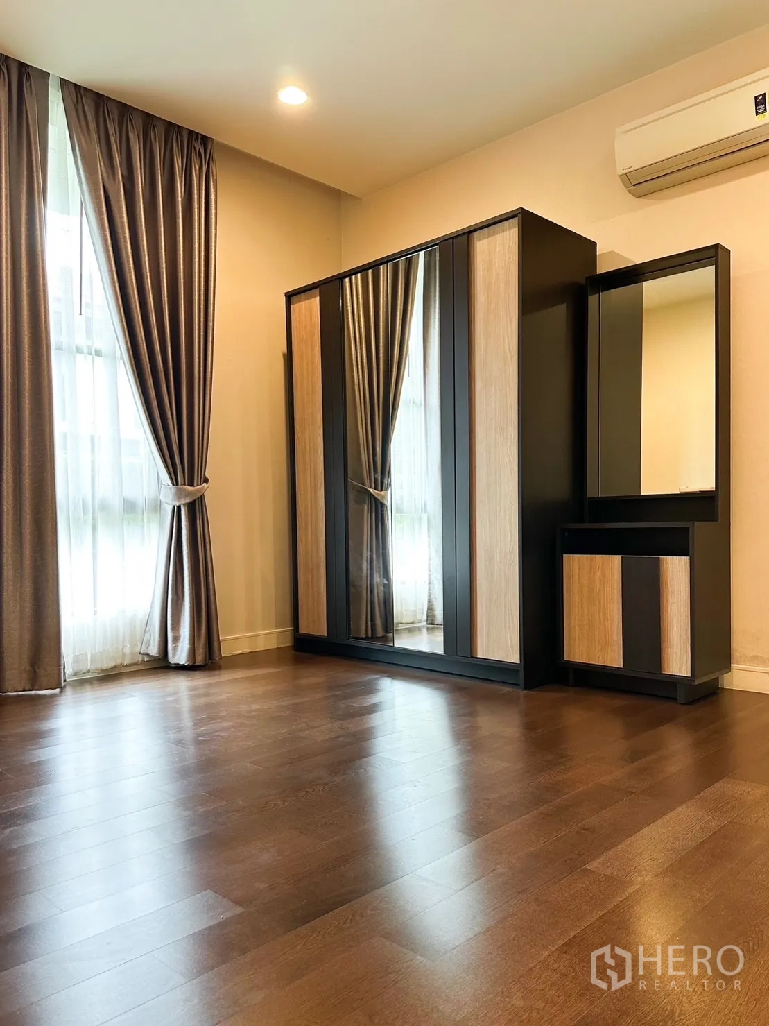 Detached House for rent or sale in Bang Kapi, Bangkok - Spacious bedroom with mirrored wardrobe, vanity and curtains.