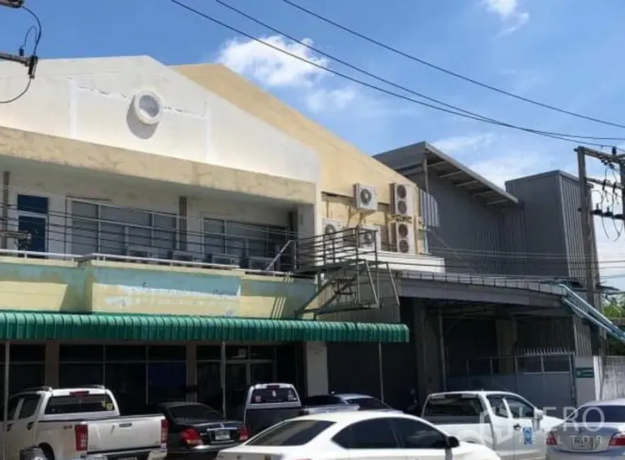 Factory for rent or sale in Khlong Luang, Pathum Thani - Two-storey factory facade in Khlong Luang with covered loading bay, exterior AC units and on-site parking.