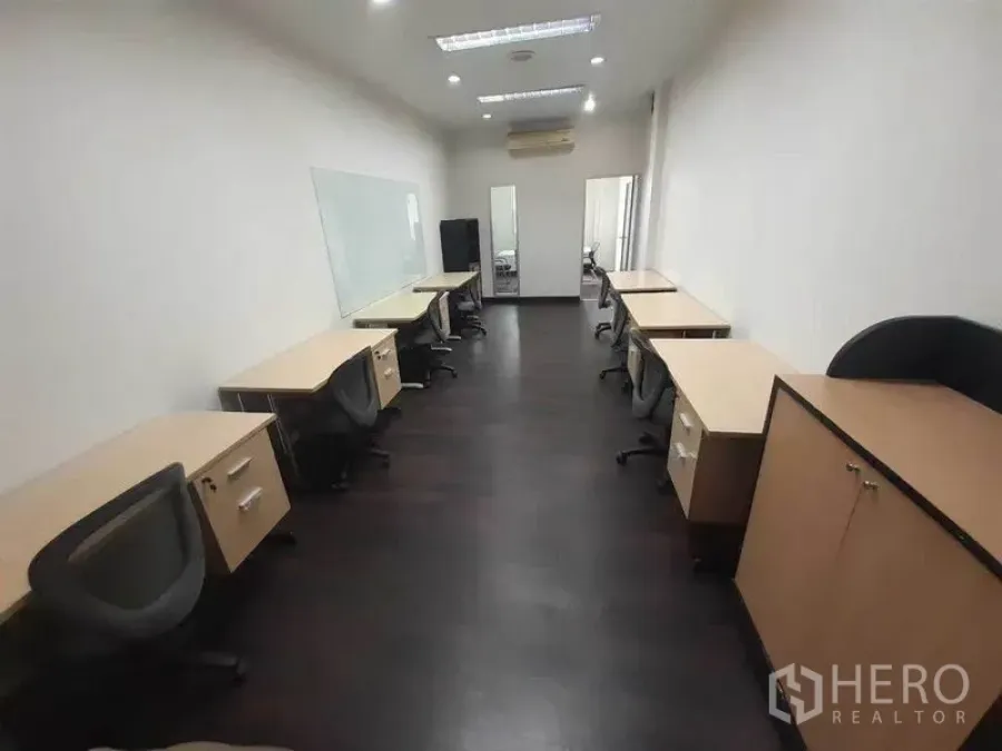 Office Space for rent in Khlong Toei, Bangkok - Furnished office with multiple desks and chairs, large whiteboard, dark wood flooring, recessed lighting, and air conditioner.