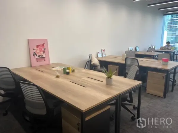 Office Space for rent in Pathum Wan, Bangkok - Bright workspace featuring wood tables, task chairs and a clean white wall.