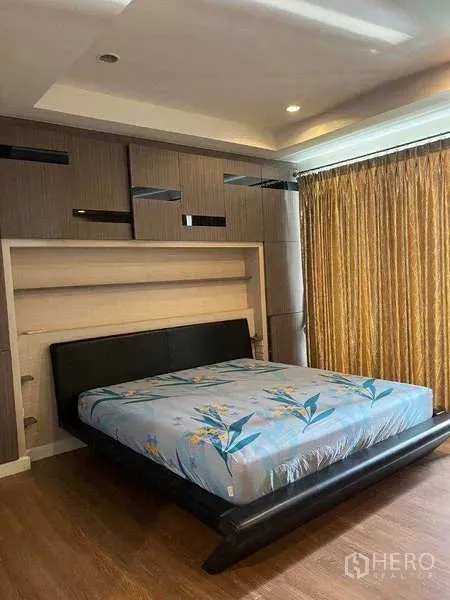 Townhouse for rent in Khlong Toei, Bangkok - Master bedroom with built-in headboard, king bed, and large window with gold curtains.