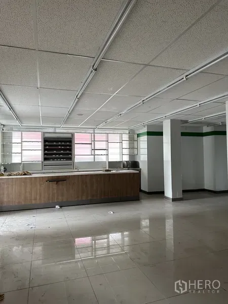 Retail Space for rent in Khlong Toei, Bangkok - Ground-floor retail hall with a long wooden service counter and wide windows.