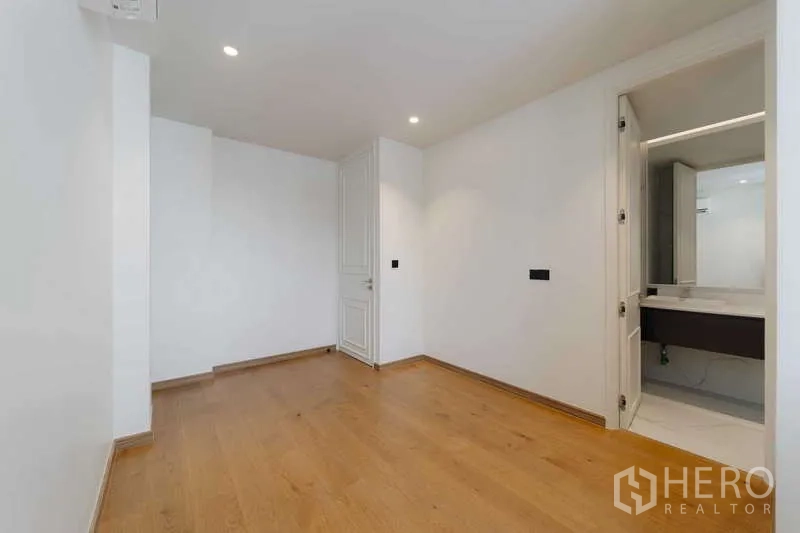 Townhouse for rent or sale in Watthana, Bangkok - Flexible room with en-suite access, recessed lighting, and wood floors.
