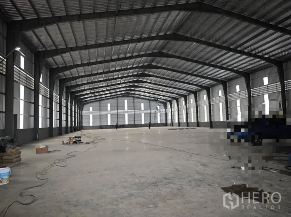 Warehouse for rent or sale in Bang Phli, Samut Prakan - Open clear-span warehouse interior with high steel truss roof and concrete floor.