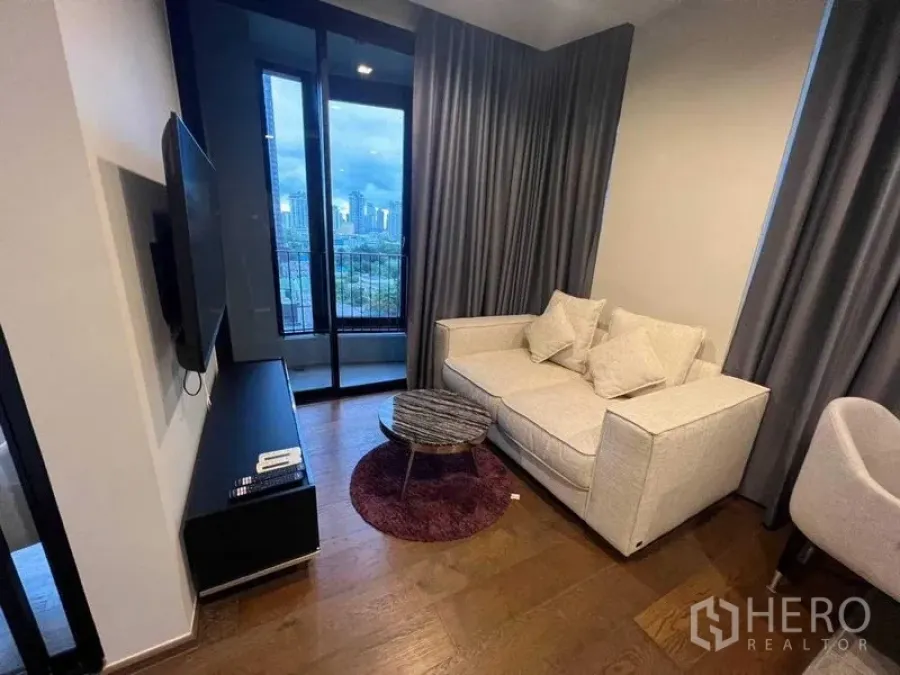 Condominium for rent in Khlong Toei, Bangkok - Another view of the living room with sofa, TV console and balcony skyline.