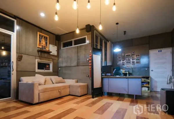 货栈 出租在Bueng Kum, Bangkok - 舒适的办公室休息区，配沙发、办公桌与水泥风墙面与暖色吊灯。