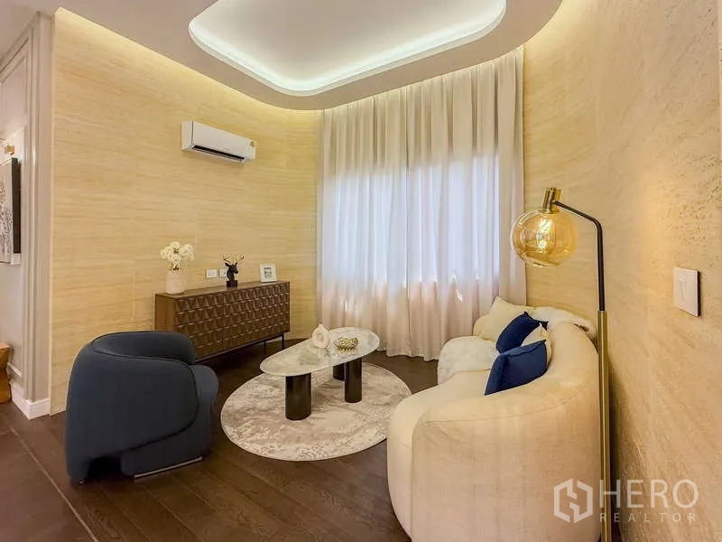 独立式住宅 出租或出售在Bang Kapi, Bangkok - 温馨会客角，弧形沙发、单椅与圆形茶几。