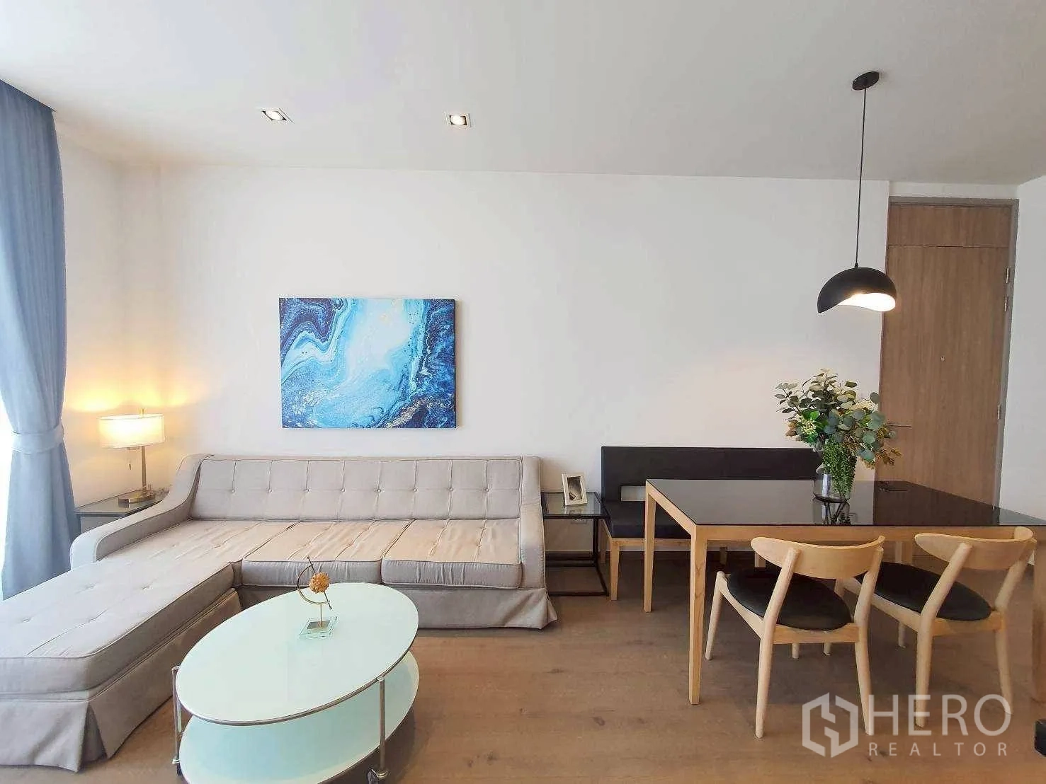 Condominium for rent in Khlong Toei, Bangkok - Open-plan living and dining area with an L-shaped sofa, glass coffee table, and dining set.