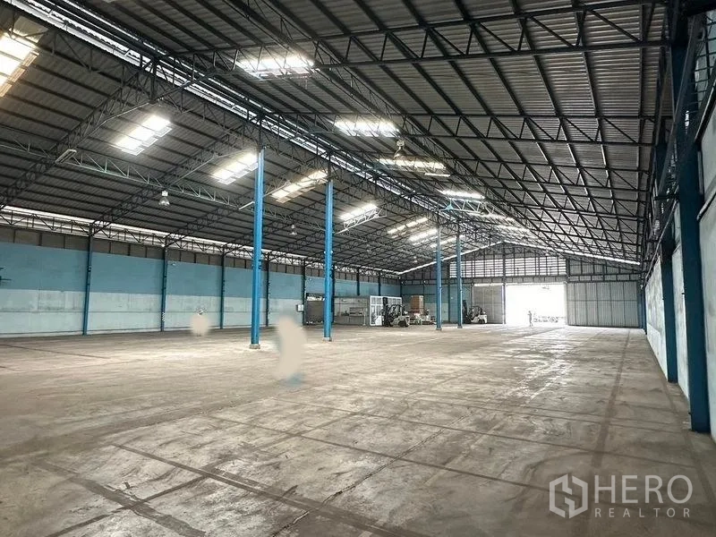 Warehouse for rent in Bang Pa-in, Phra Nakhon Si Ayutthaya - Expansive clear-span storage space with bright roof panels and rear access door.