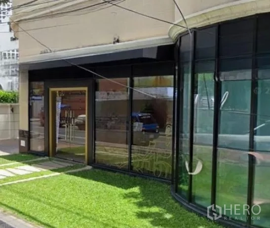 Retail Space for rent in Watthana, Bangkok - Close view of entrance and curved display windows beside green lawn.