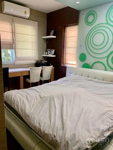 Detached House for rent in Prawet, Bangkok - Cozy bedroom with white bed, study desk, and green circular accent wall.