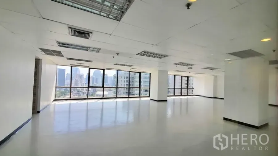 Office Space for rent in Watthana, Bangkok - Bright open-plan office with floor-to-ceiling windows, city skyline views, and a grid ceiling with fluorescent lighting and air vents.