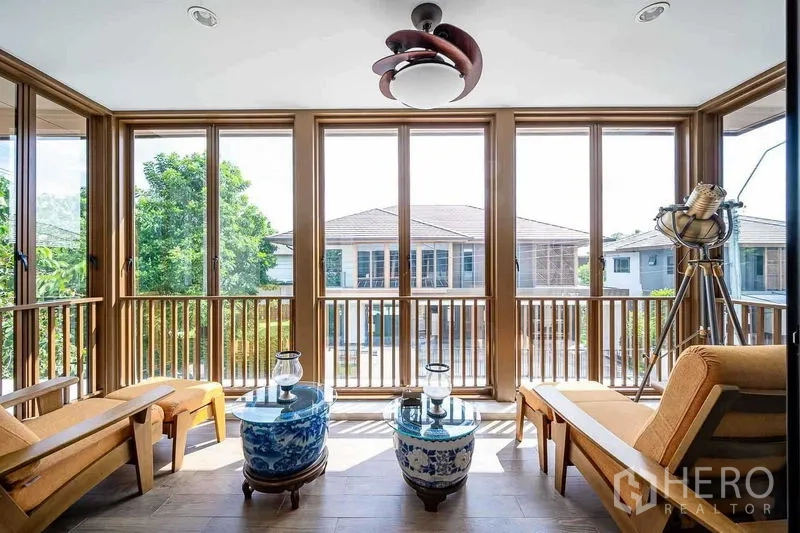 Detached House for sale in Prawet, Bangkok - Bright sunroom with floor‑to‑ceiling windows, lounge chairs and a modern pendant light.