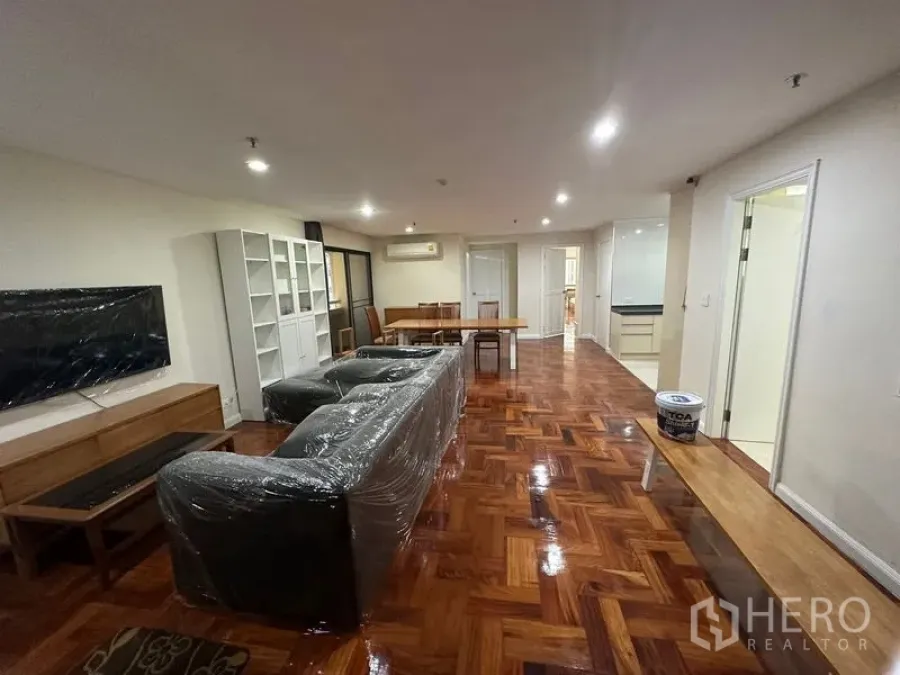 คอนโด ให้เช่าในWatthana, Bangkok - ห้องนั่งเล่นและทานข้าวแบบเปิดโล่ง โซฟา ผนังติดทีวี ชั้นวางของ และพื้นปาร์เกต์เงา