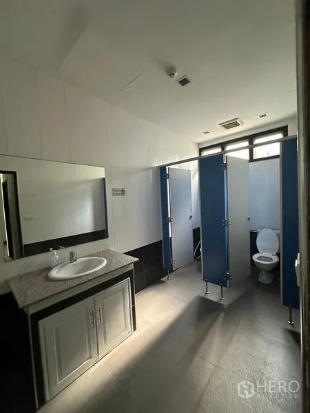 Warehouse for rent in Prawet, Bangkok - Bright restroom showing toilet stalls and a single vanity.