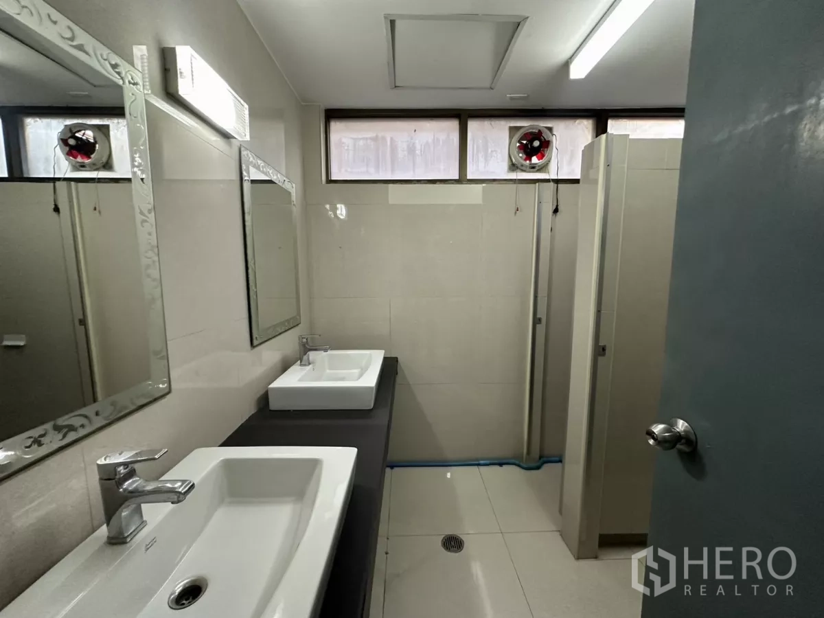 Office Space for rent - Clean restroom area with sinks, mirrors and cubicle doors.