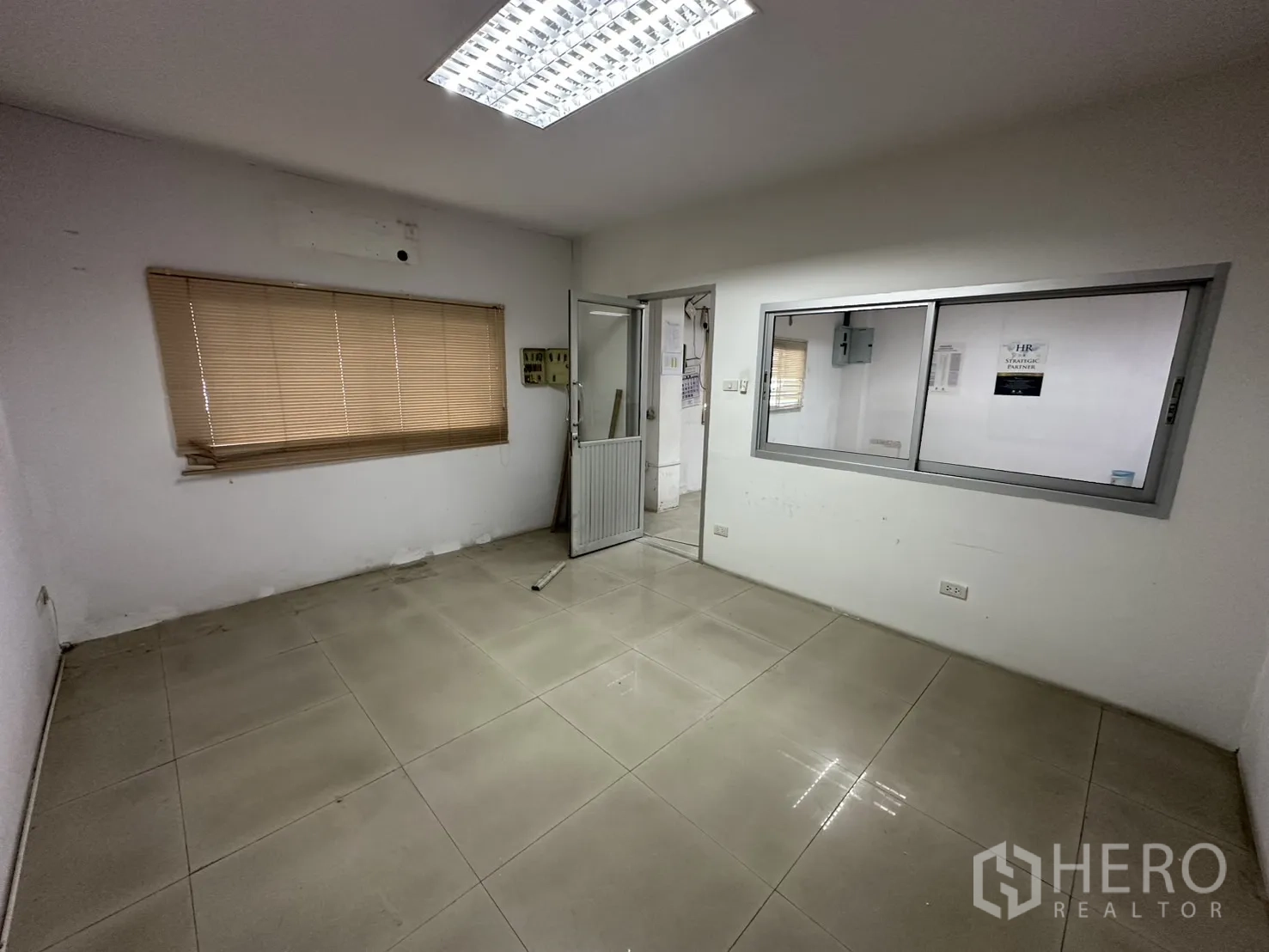 Factory for rent - Compact office room with window blinds and tiled floor.