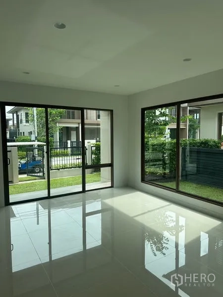 Detached House for rent in Bang Kapi, Bangkok - Sunlit living room with glossy tile floors and corner sliding doors to the garden.