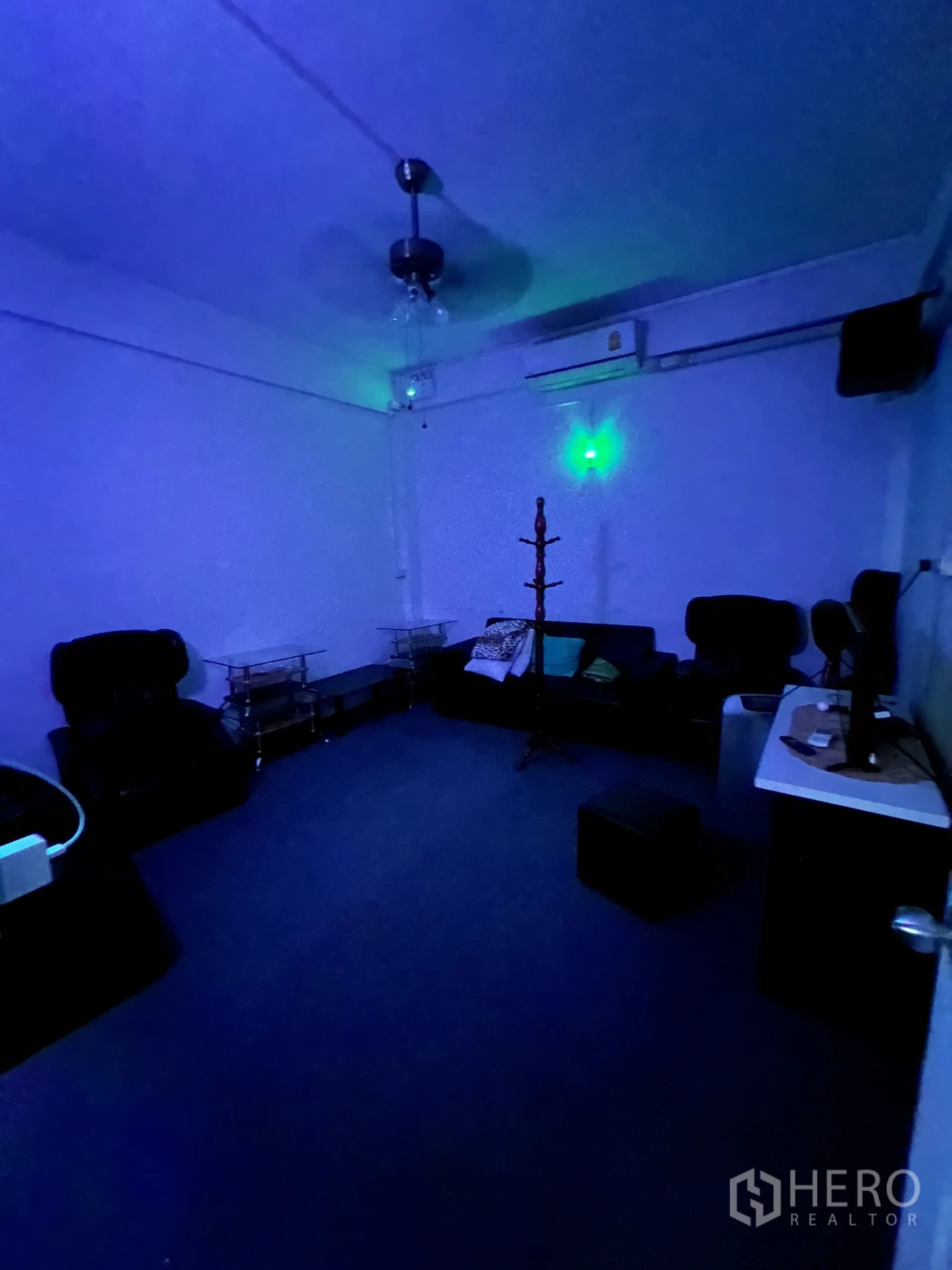 Shophouse for rent in Khlong Toei, Bangkok - VIP lounge under blue lighting with sofas, ceiling fan and AC unit.