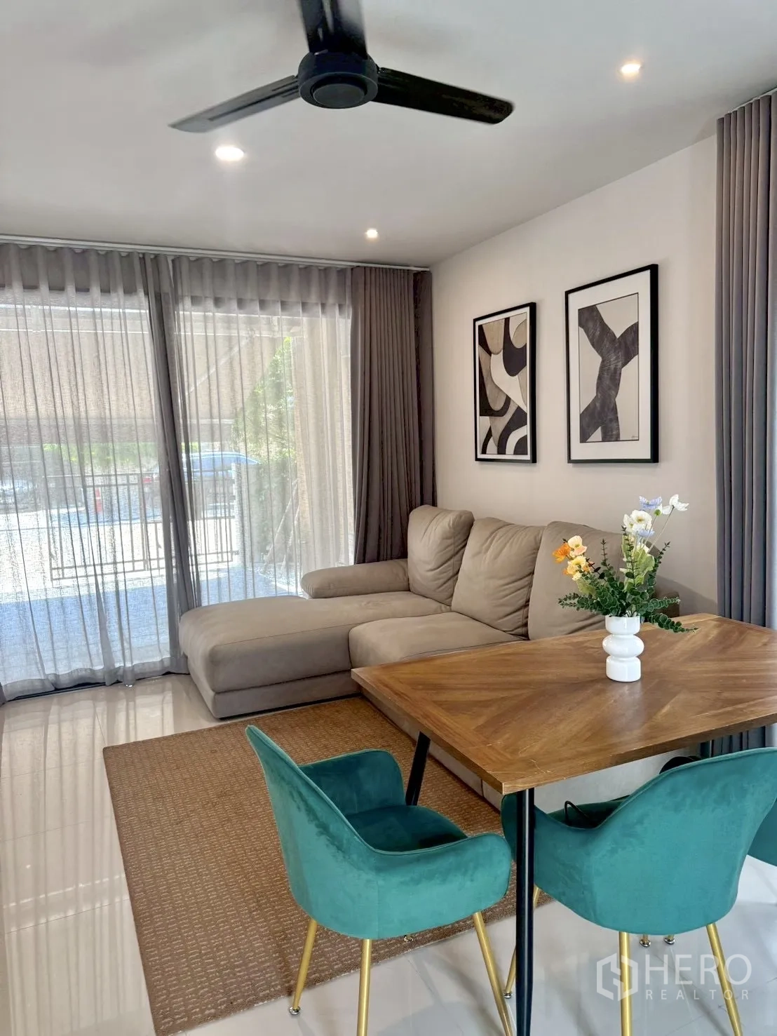 Townhouse for rent in Prawet, Bangkok - Bright living area with L-shaped sofa, dining table, ceiling fan and sheer curtains.