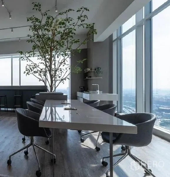 Office Space for rent - Pantry and breakout area with long counter, swivel chairs, indoor tree and full-height windows overlooking Bangkok.