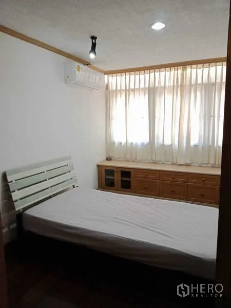 Townhouse for rent in Khlong Toei, Bangkok - Cozy bedroom with bed, storage cabinets, and sheer curtains.