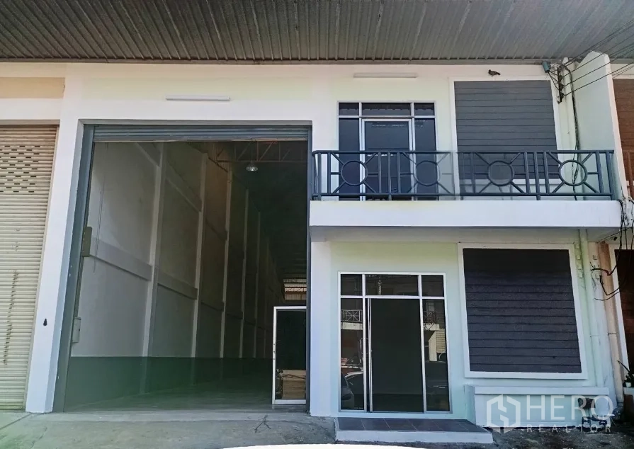Warehouse for rent in Bang Phli, Samut Prakan - Warehouse exterior with wide roller shutter, balcony and separate glass entry.
