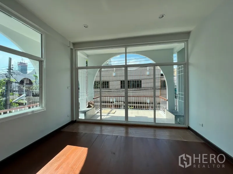 Home Office for rent in Watthana, Bangkok - Bright living area with floor-to-ceiling glass doors opening to an arched terrace.