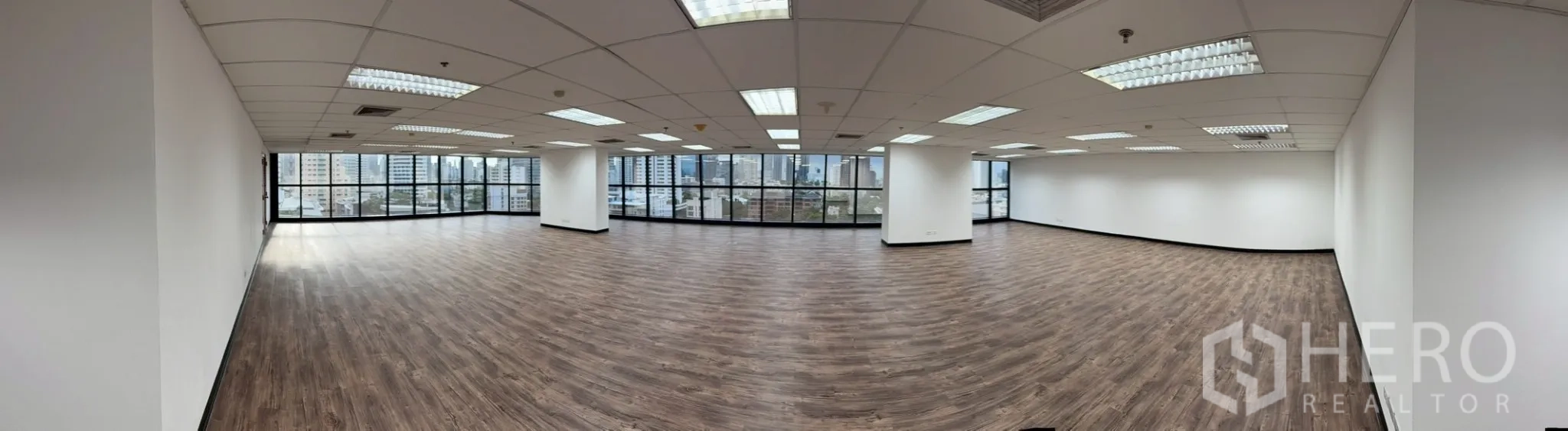 Office Space for rent in Watthana, Bangkok - Panoramic open-plan office with wood-look floors, grid ceiling lights, and wide city views.