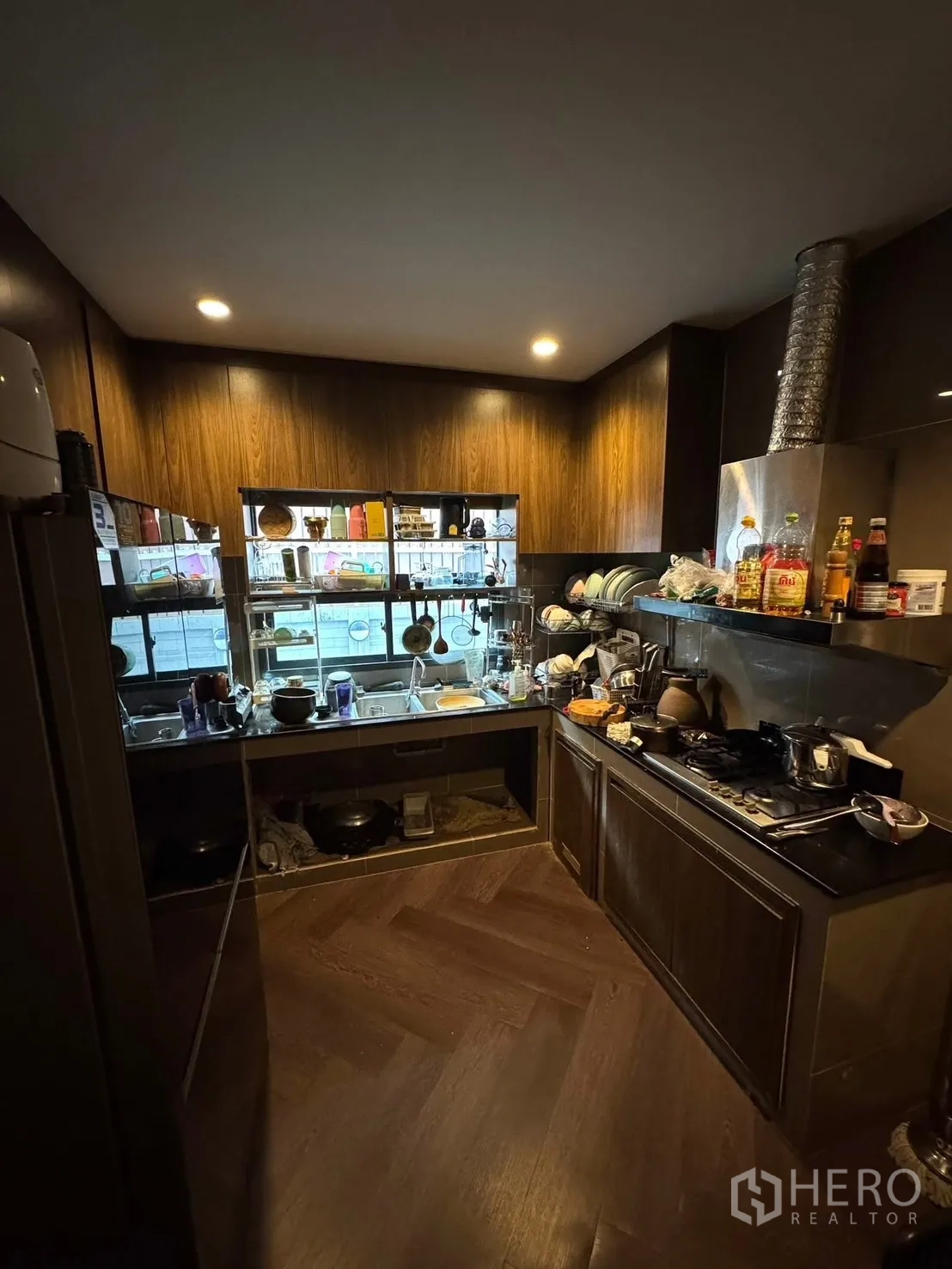 Detached House for sale in Mueang Pathum Thani, Pathum Thani - Enclosed Thai kitchen with gas hob, range hood and dark cabinetry.