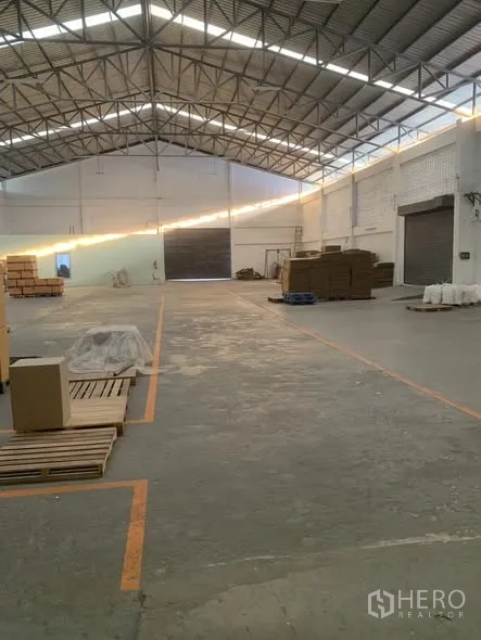 Warehouse for rent in Bang Phli, Samut Prakan - Open warehouse aisle leading toward large roller shutter loading doors.