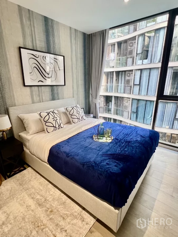 Condominium for rent in Khlong Toei, Bangkok - Master bedroom with large bed, big windows and views of the curved building facade.
