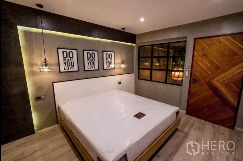 Townhouse for rent in Khlong Toei, Bangkok - Third bedroom with accent lighting, framed wall art, wooden door and window panel.