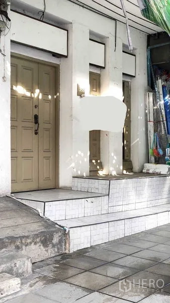 Shophouse for rent in Suan Luang, Bangkok - Street-level storefront entrance with steps, double doors and a tiled platform.