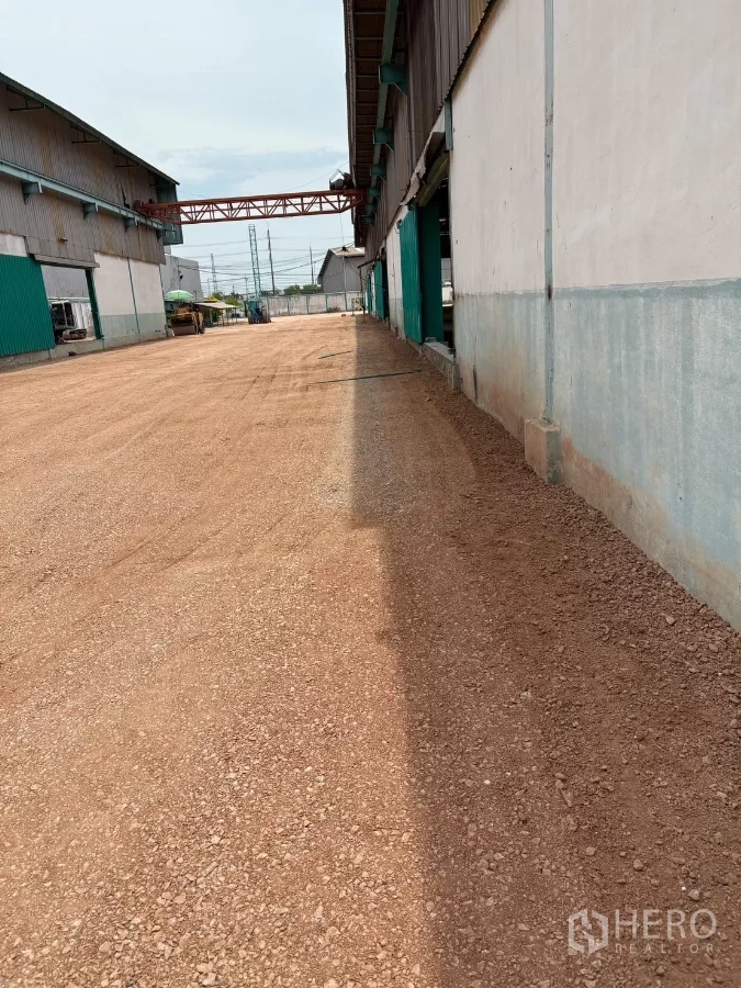 Factory for rent in Mueang Samut Sakhon, Samut Sakhon - Long side access lane beside the factory with compacted gravel surface and utilities.