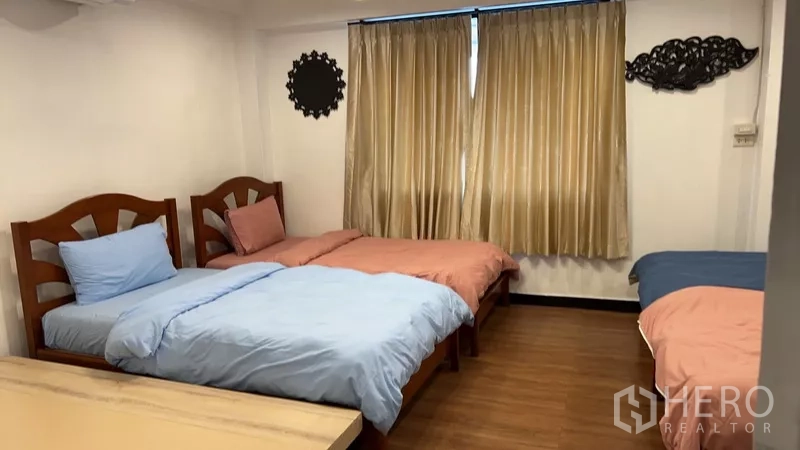 Home Office for rent or sale in Phra Khanong, Bangkok - Bedroom with multiple single beds, warm curtains and wood-look flooring.