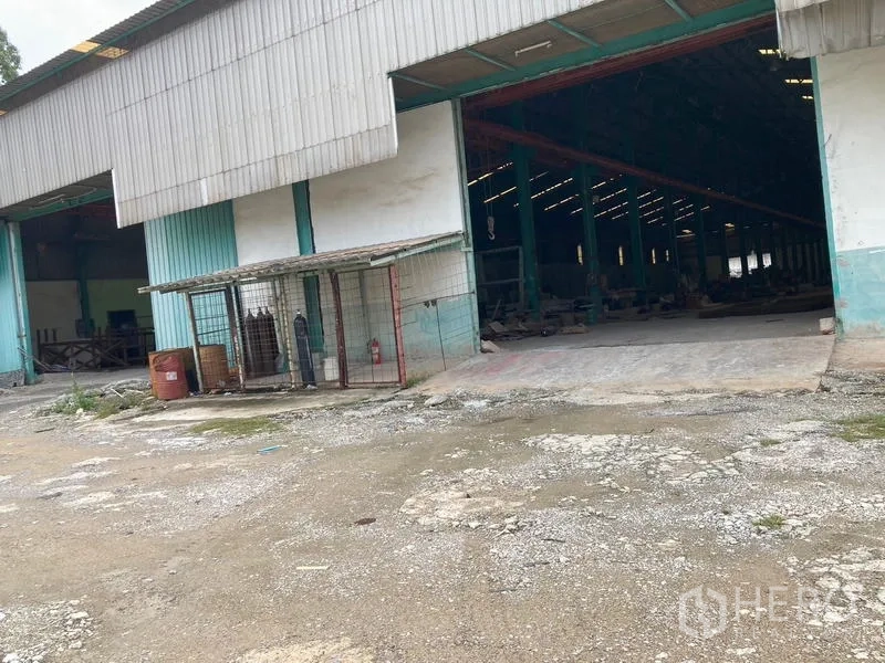 Warehouse for rent in Mueang Samut Sakhon, Samut Sakhon - Multiple loading bays and a covered storage cage beside a wide yard at the warehouse.