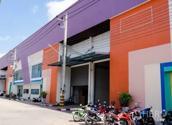 Factory for rent in Mueang Samut Sakhon, Samut Sakhon - Colorful factory facade with large roller shutter door, covered loading bay and parking area in Samut Sakhon.