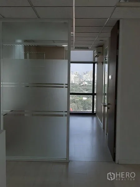 Office Space for rent in Bang Rak, Bangkok - Hallway with frosted glass partitions leading to a bright windowed room.