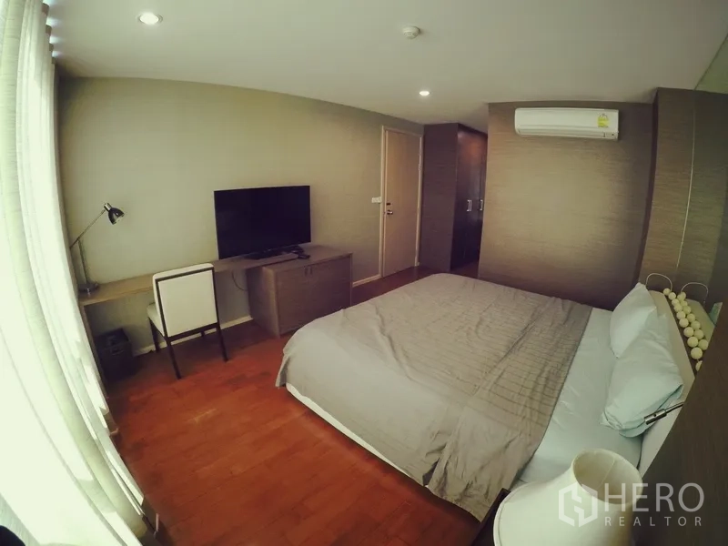 Condominium for rent or sale in Khlong Toei, Bangkok - Bedroom with double bed, TV, work desk, wardrobe and air-conditioning over warm wood floors.