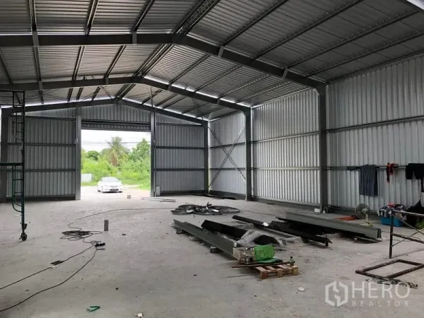 Warehouse for rent in Bang Yai, Nonthaburi - Open‑plan warehouse facing large double doors with natural light and a car outside.