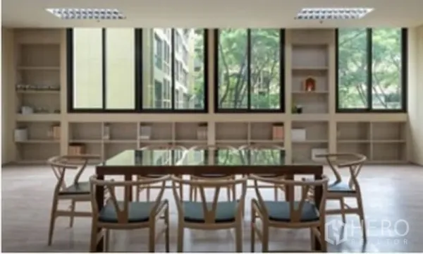 Office Space for rent in Chatuchak, Bangkok - Modern meeting area with glass-top table, wooden chairs, built-in shelves and wide windows overlooking greenery.