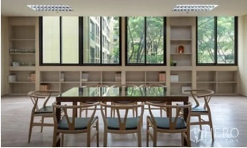 Office Space for rent in Chatuchak, Bangkok - Modern meeting area with glass-top table, wooden chairs, built-in shelves and wide windows overlooking greenery.