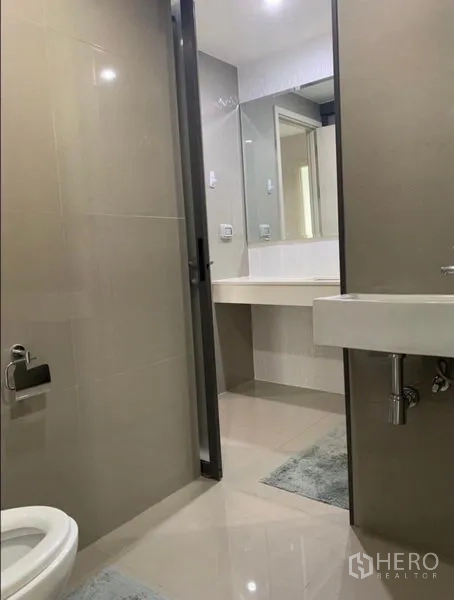 Condominium for rent in Khlong Toei, Bangkok - Bathroom second angle featuring toilet, slim washbasin, and view toward the vanity area.