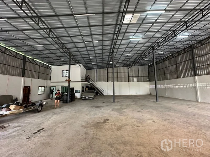 Warehouse for rent in Thanyaburi, Pathum Thani - Wide interior bay with steel columns, staircase to mezzanine and ample clear floor space.