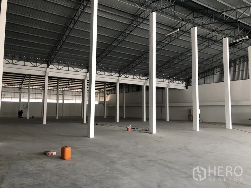 Warehouse for rent in Nonthaburi - Open-plan warehouse interior from another angle highlighting the column grid and mezzanine area.