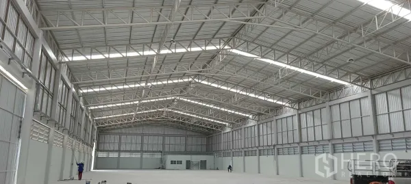 Warehouse for rent or sale in Lam Luk Ka, Pathum Thani - Spacious warehouse interior with high steel truss roof and skylights.