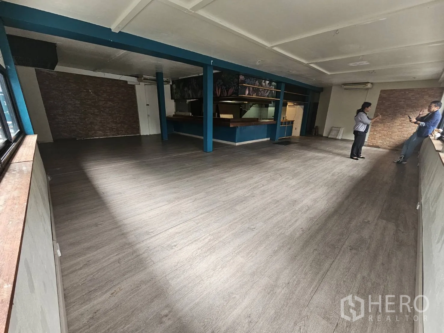 Retail Space for rent in Watthana, Bangkok - Spacious hall with wood flooring, brick accent wall and service bar area.
