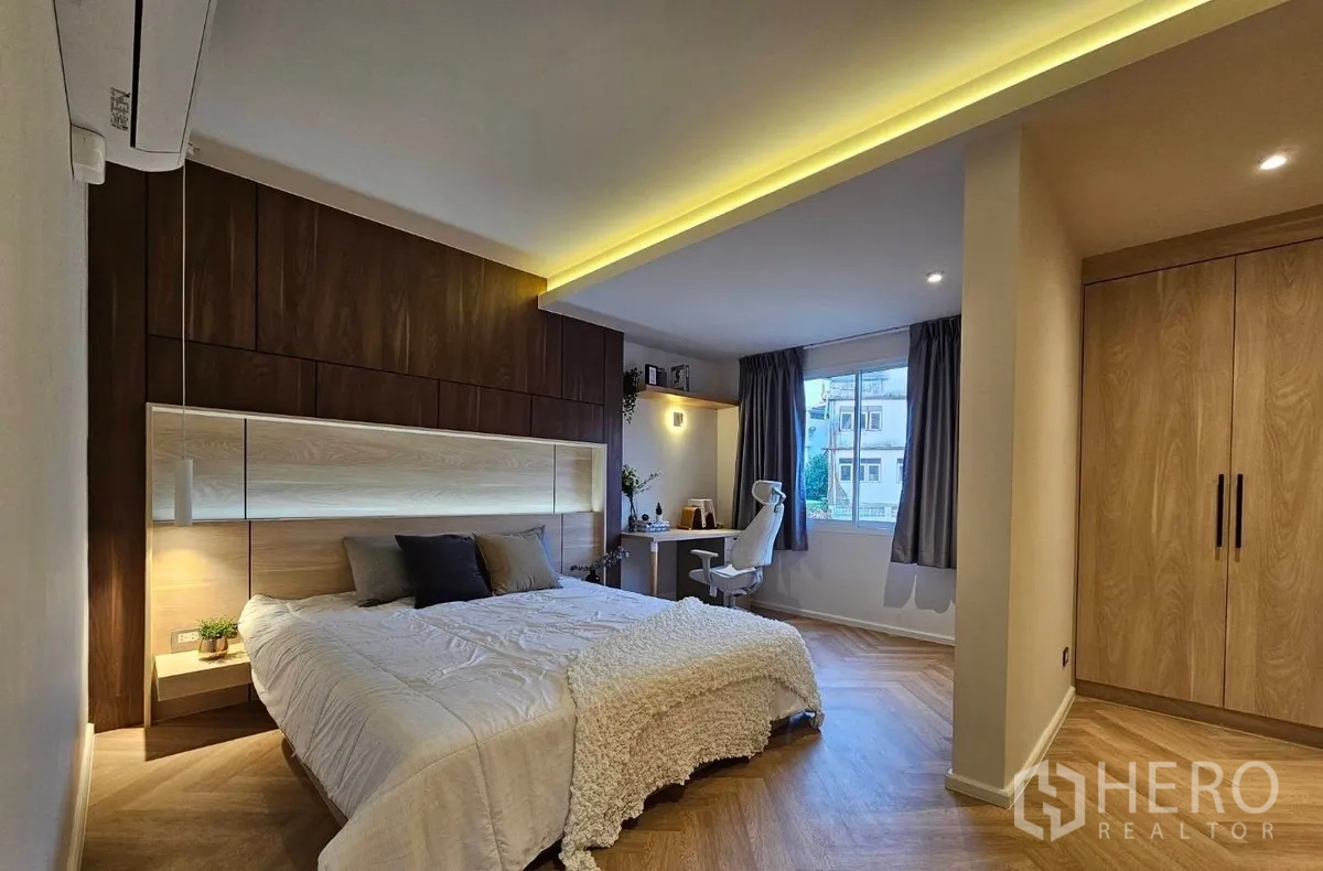 Townhouse for rent or sale in Watthana, Bangkok - Spacious master bedroom with wood panel headboard, built-ins and work desk.