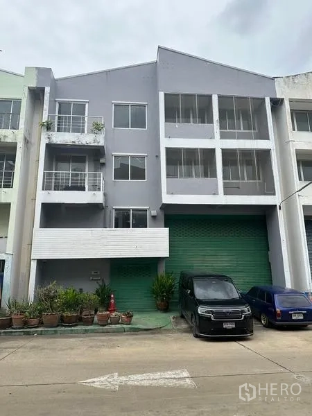 工厂 出租或出售在Khlong Luang, Pathum Thani - 三层工厂外立面，绿色卷闸门与停车位，位于空銮县。